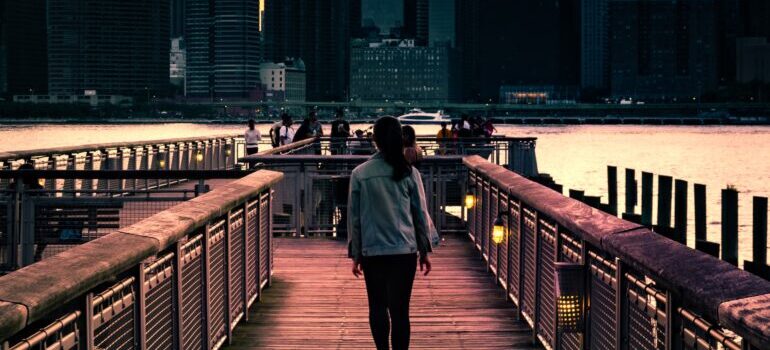 a woman is walking across the pier at the waterfront in Long Island City