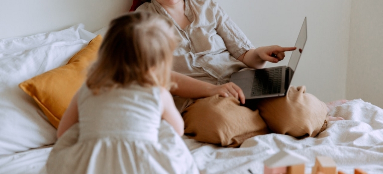 Mother thinking about moving from Chelsea to Soho while showing your kid a photo on the laptop. 