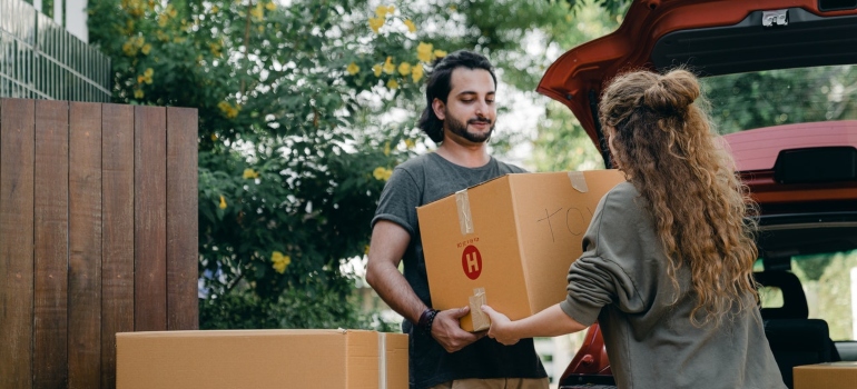 Two people carrying moving box as a symbol of how Roslyn movers can help you