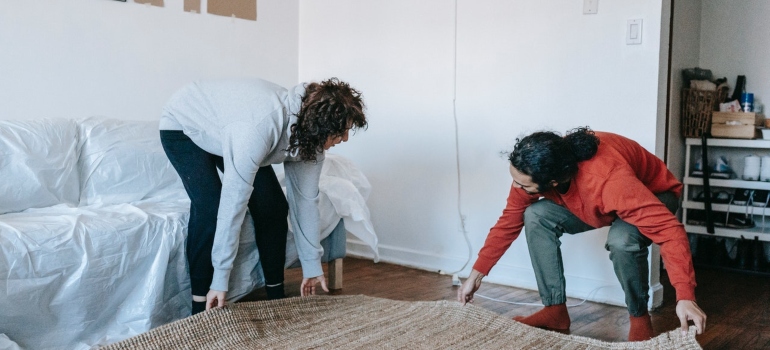 two people laying down a carpet