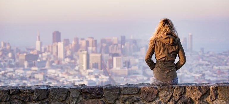a woman looking at the city from a stone wall