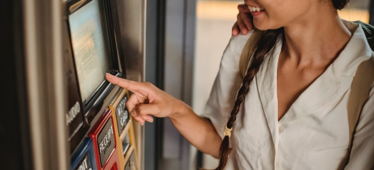 a girl using the ticket machine after reading commuter's survival guide for NYC
