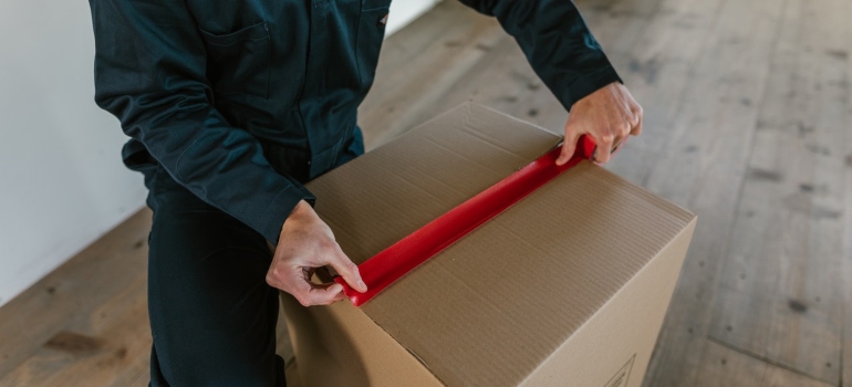 a man sealing a box with a duct tape