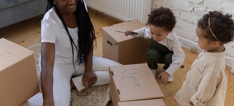A woman and two children drawing on boxes while relocating long distance as a single parent