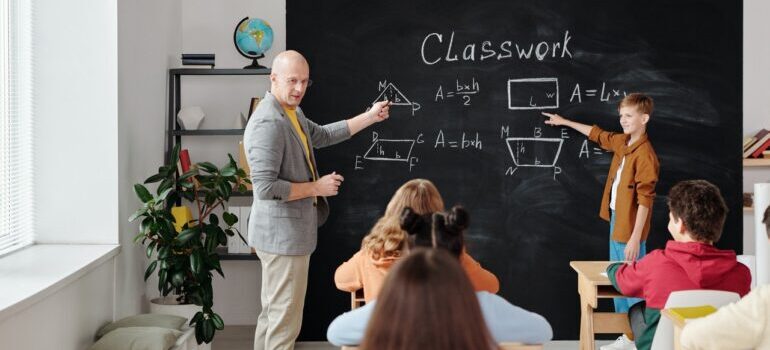 Teacher showing something on the blackboard to kids