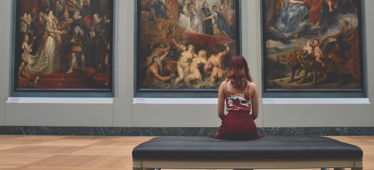 A woman is sitting while enjoying the art.
