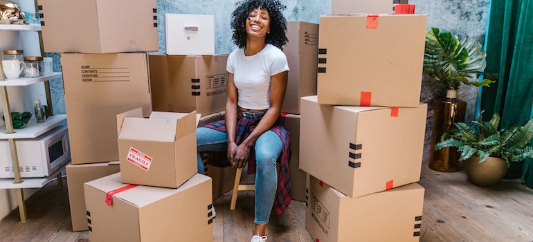Woman smiling and sitting among packed boxes