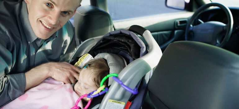 Man moving with a baby in a car safety seat. 