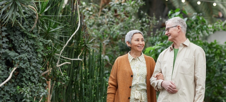 senior couple walks in botanical garden in one of the best NYC neighborhoods for retirees
