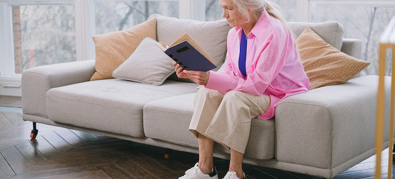 Elderly woman reading on sofa.