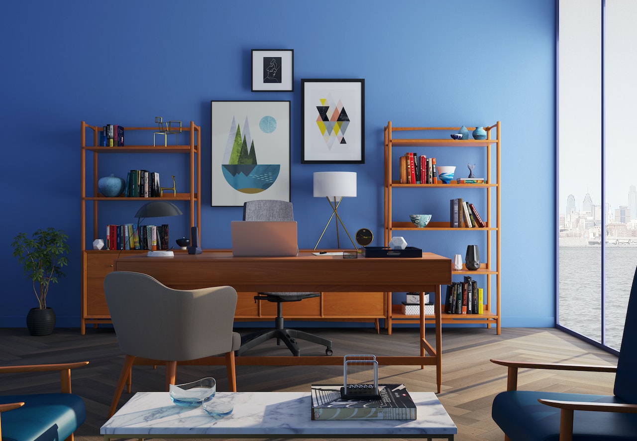 A well-decorated home office in a new Manhattan apartment with a wooden desk and blue walls.