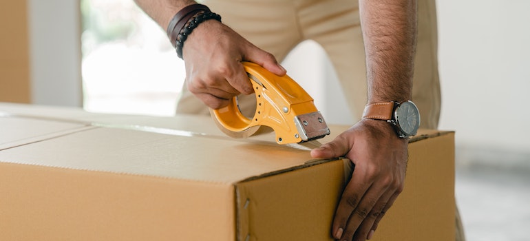 A person taping a box.